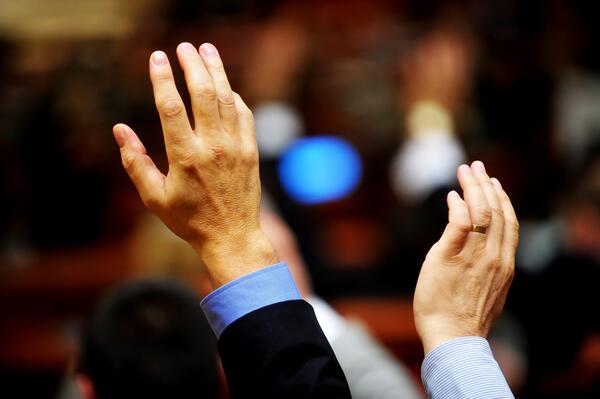 Abgebildet sind Hände zweier Personen, die im Rahmen einer Abstimmung mit Handzeichen ihre Zustimmung signalisieren.